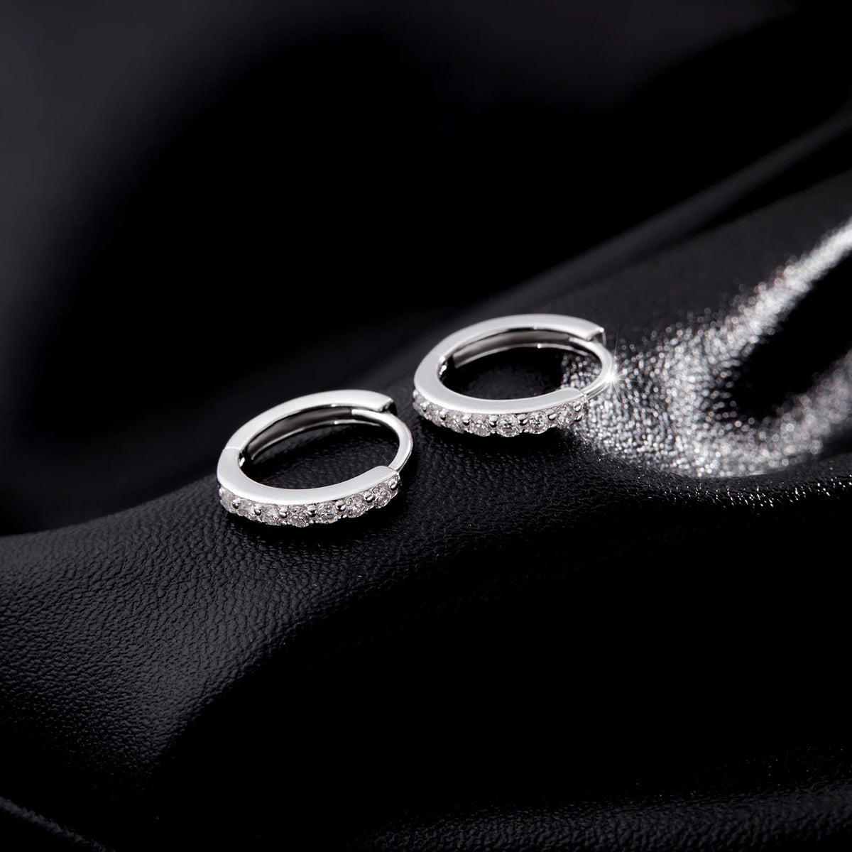 Lab-Created Moissanite Eternity Hoop Earrings, pair lying flat on black satin