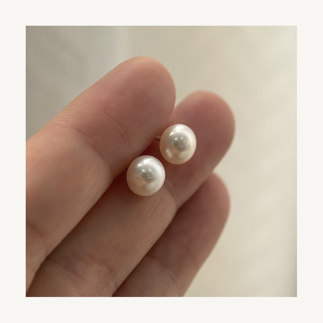Cultured freshwater pearl stud earrings held in hand